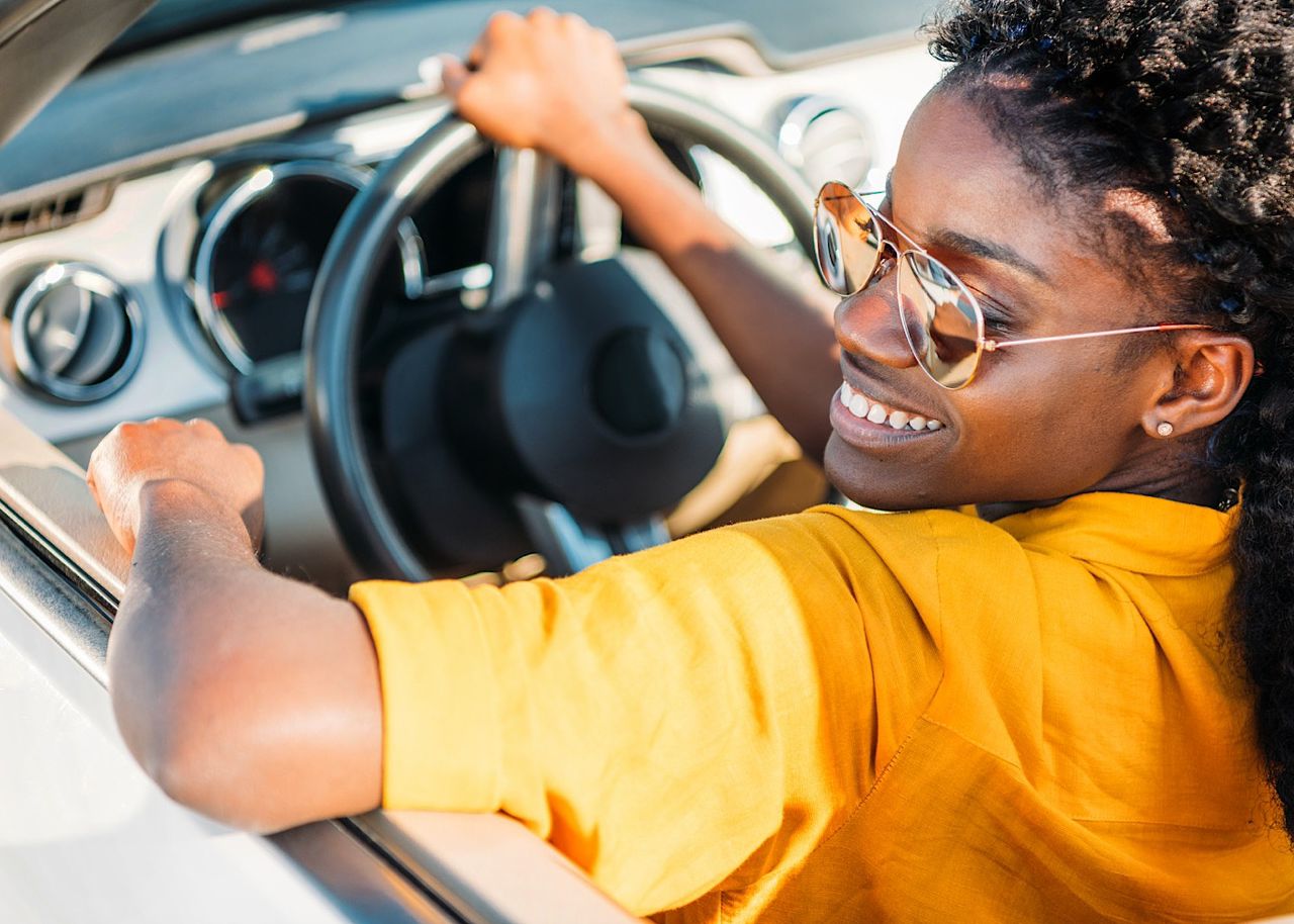 portrait of smiling african american woman in sunglasses riding car by LightFieldStudios